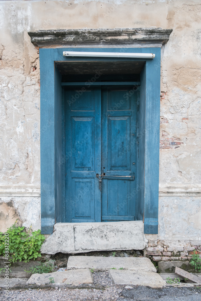 Old wooden blue door in the wall of old building.