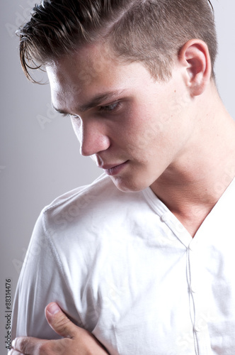 Handsome young man with fashion hairstyle over gray background. © bulashenko