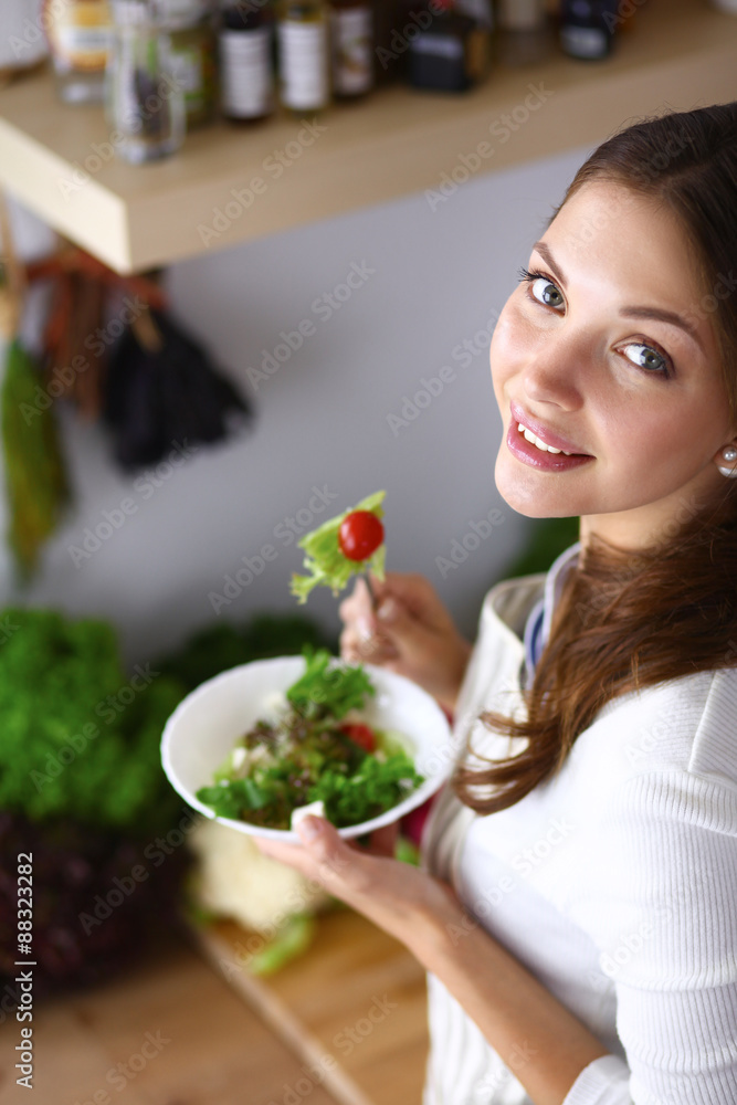 Young woman eating salad and holding a mixed salad 