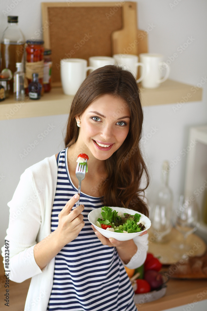 Young woman eating salad and holding a mixed salad 
