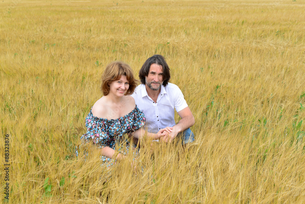 Loving middle-aged couple standing in field in summer Loving middle-aged couple standing in field in summer