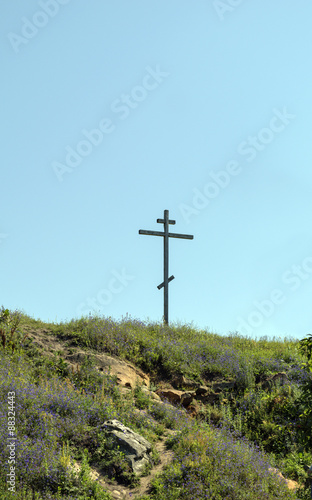 Big old wooden cross on a hill on a clear blue cloudless sky