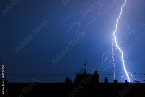 Lightning hitting city building rooftop in thunderstorm