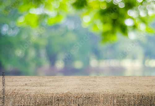 Tableau sur toile Empty table covered with sackcloth over blurred trees with bokeh