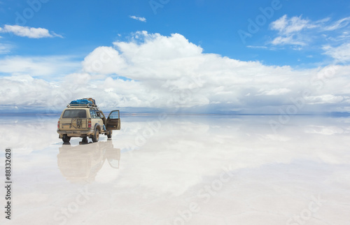 Car on the reflected surface of Salar de Uyuni lake in Bolivia photo