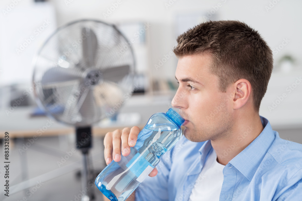 mann trinkt wasser im büro mit ventilator im hintergrund Stock Photo |  Adobe Stock