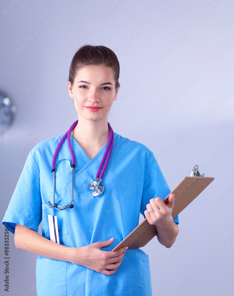 Smiling female doctor with a folder in uniform standing at Smiling female doctor with a folder in uniform standing at