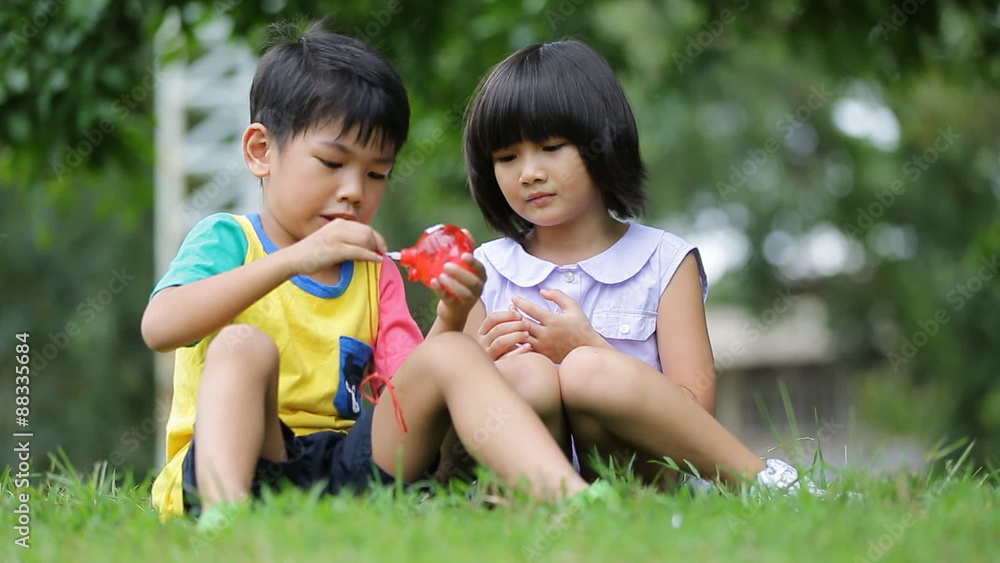 Little asian boy and girl blowing soap bubble in the park Little asian boy and girl blowing soap bubble in the park