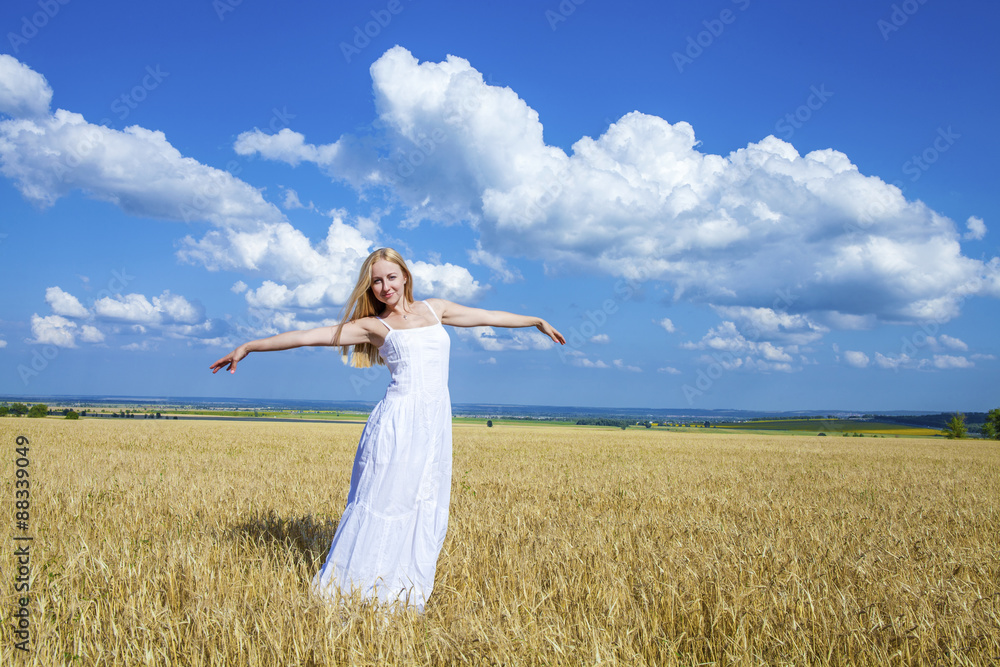 Young beautiful woman in a long white dress is standing in a whe Young beautiful woman in a long white dress is standing in a whe