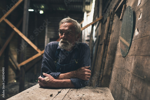 Lonely farmer sitting inside a wooden barn