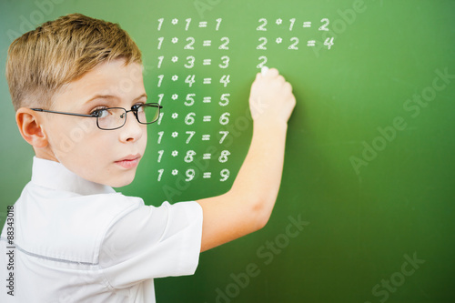 Картината върху платно First grade schoolboy wrote multiplication table on blackboard