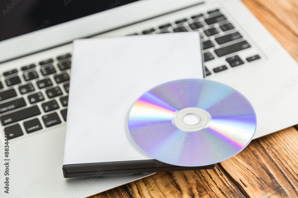 Blank compact disc with cover on laptop keyboard Blank compact disc with cover on laptop keyboard