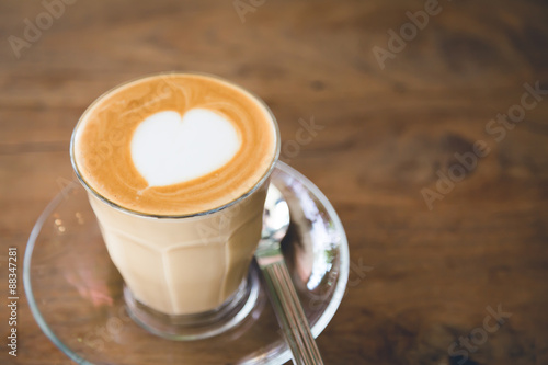 Cup of coffee with heart pattern on wood table ( Filtered image