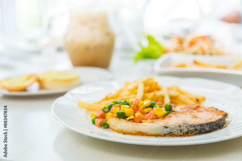 Grilled salmon steak meal served with salad and French fries Grilled salmon steak meal served with salad and French fries