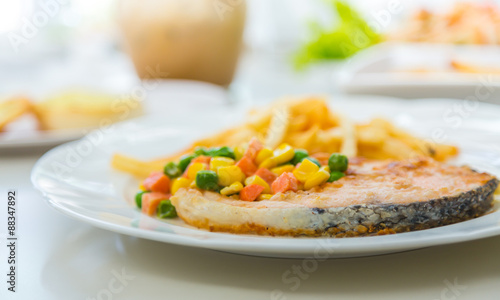 Grilled salmon steak meal served with salad and French fries