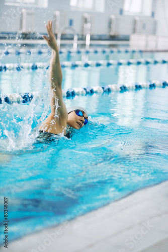 Young girl in goggles swimming front crawl stroke style