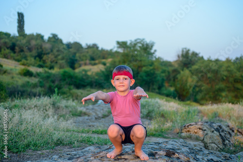 Fototapeta Naklejka Na Ścianę i Meble -  Supple young boy practicing pilates outdoors