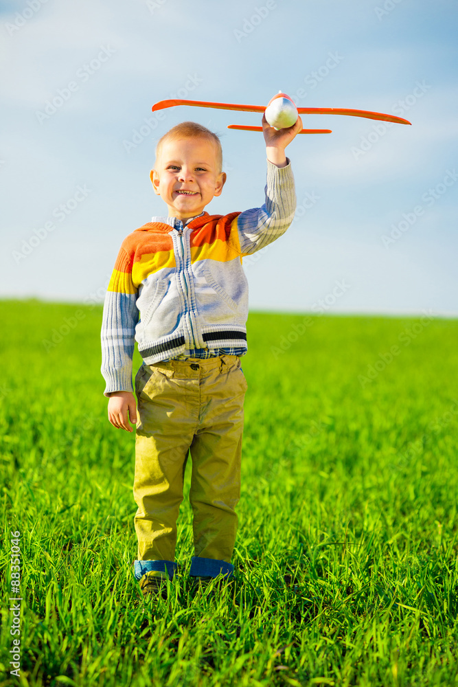 Happy boy playing with toy airplane against blue summer sky and Happy boy playing with toy airplane against blue summer sky and