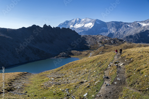 Hikers walking on the Colle del Nivolet beside Rossett Lake (Lago Rossett), Gran Paradiso National Park, Alpi Graie (Graian Alps)  photo