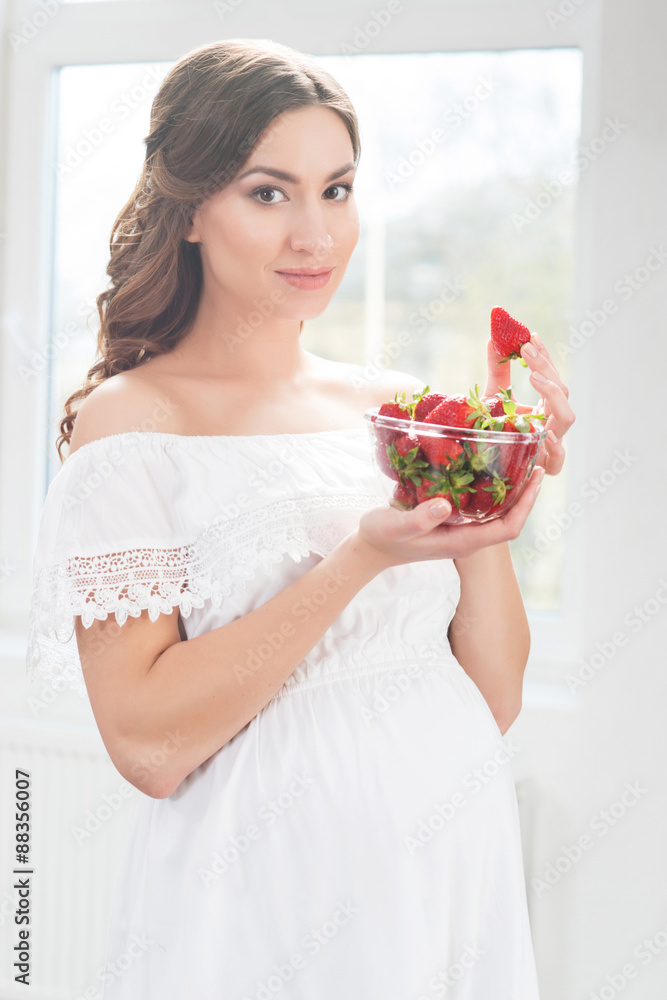 Beautiful pregnant woman with a bowl of strawberries. Beautiful pregnant woman with a bowl of strawberries.
