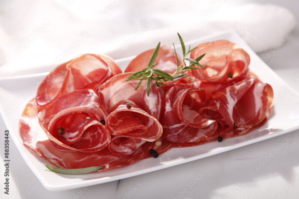 Dried sausage on a plate and a wooden white board 