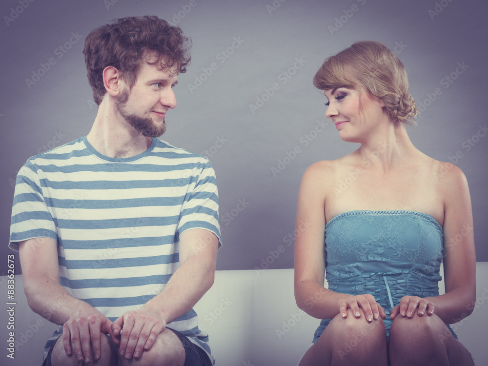 Shy woman and man sitting close to each other on couch. Shy woman and man sitting close to each other on couch.