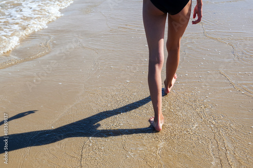 Beine eines jungen Mädchens dass am Strand läuft photo