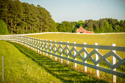 Photography white fence leading up to a big red barn
