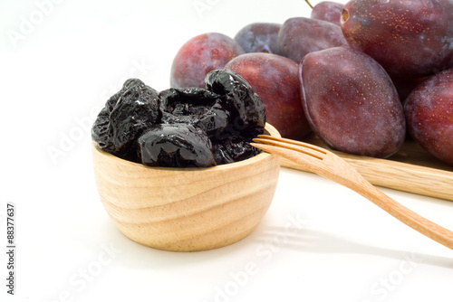 Delicious prunes in wooden bowl and fresh plums