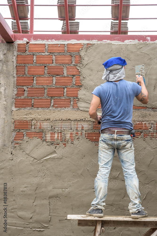 Builder worker plastering concrete at wall Builder worker plastering concrete at wall