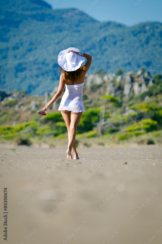 beautiful young woman takes a relaxing walk along a sandy beach 
