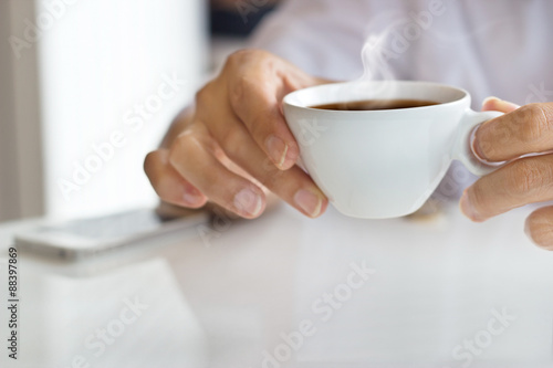 businessman and a cup of coffee in hand, blank text and soft focus