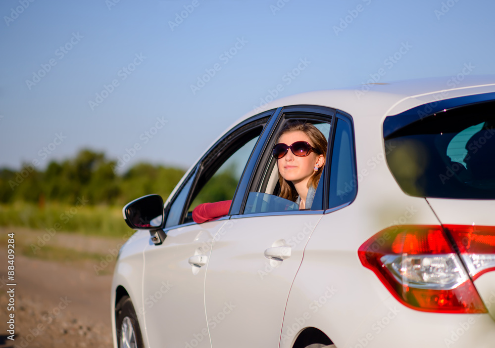 Fototapeta premium Smiling young lady in a car