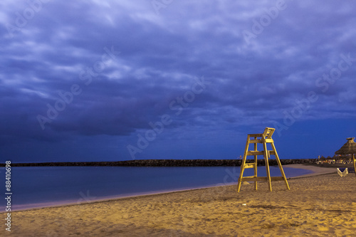 High wooden lifesaver chair on tropical sandy deserted beach night shoot