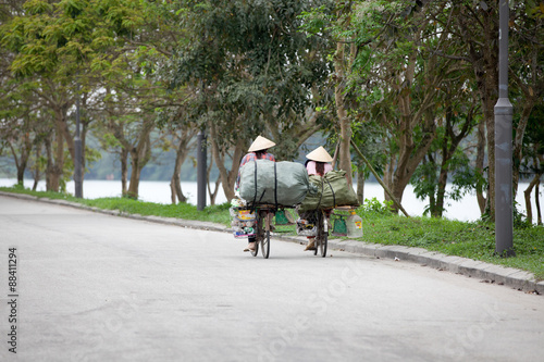 Hue, Vietnam - March 10, 2014: Two vietnamese women riding the bicycle on the street of Hue on March 10, 2014, Vietnam.