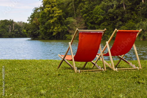 Two orange sun beds on the lake in the woods. Laxenburg, Austria.