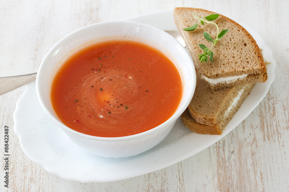 tomato soup in white bowl with sandwich on white background tomato soup in white bowl with sandwich on white background
