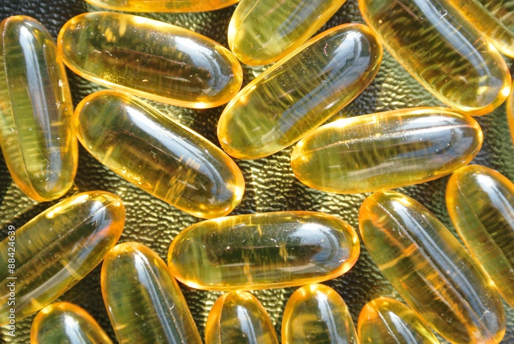 Closeup of omega 3 fish oil gel capsules on the black table, shot from above. Food supplements; essential fatty acids; healthy diet. Closeup of omega 3 fish oil gel capsules on the black table, shot from above. Food supplements; essential fatty acids; healthy diet.