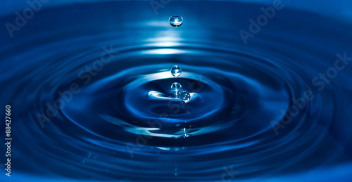 Drop falling in blue water.