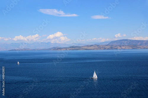 Sea view. Mountain view. View on Albania mointains. Beautiful Ionian dark blue sea. Lonely little white yacht in the middle of the sea