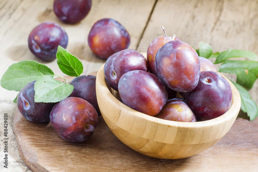 Delicious blue plums in a wooden bowl, selective focus Delicious blue plums in a wooden bowl, selective focus