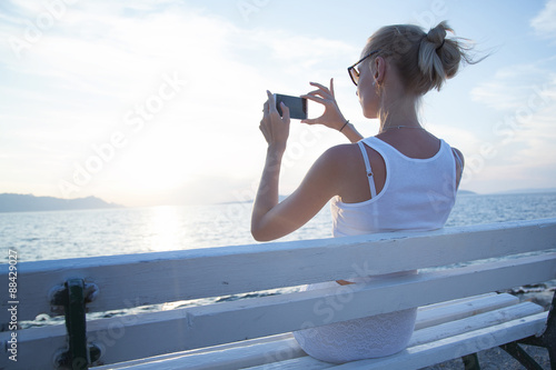 Blonde woman using cellphone on vacation.