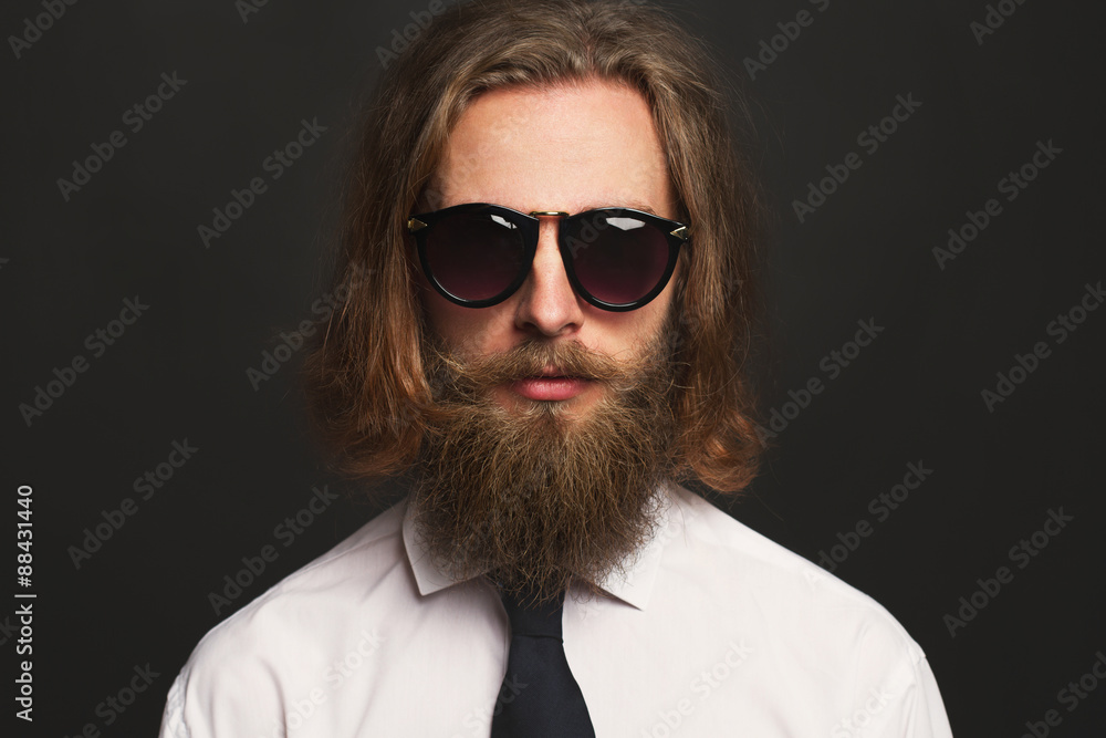 Close up stylish gorgeous young businessman with long beard with glasses on black background Close up stylish gorgeous young businessman with long beard with glasses on black background
