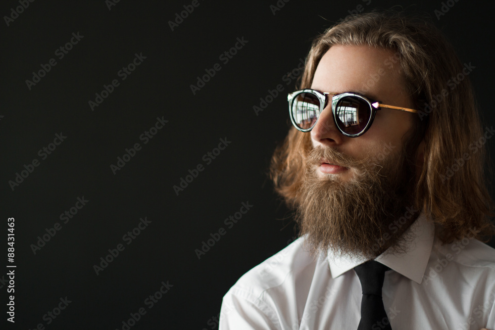 Close up stylish gorgeous young businessman with long beard with glasses on black background Close up stylish gorgeous young businessman with long beard with glasses on black background