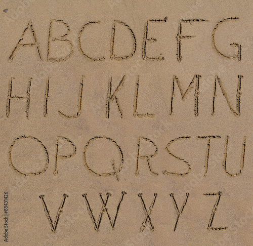 Sand alphabet letters handwritten on beach