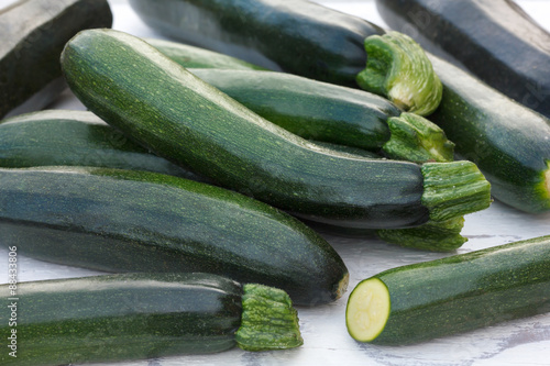 Pile of whole courgettes on white weathered wood.