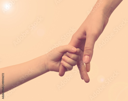 Child and mother hands together on light background