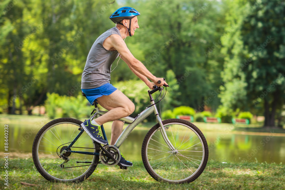 Profile shot of a joyful senior biker riding a bicycle in a park Profile shot of a joyful senior biker riding a bicycle in a park