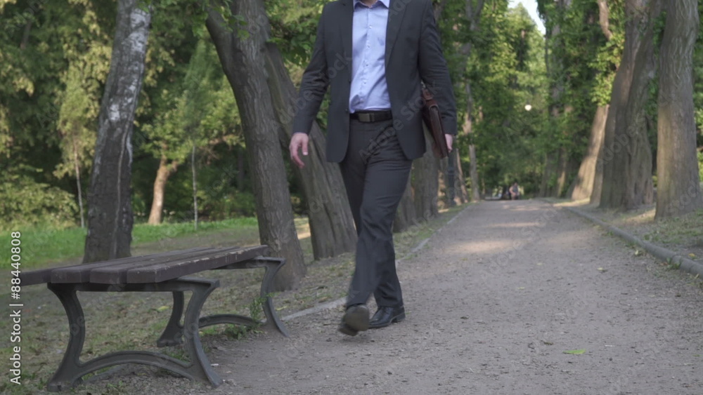 Businessman sits on bench in park and starts working with documents.
Businessman sits on bench in park and starts working with documents.