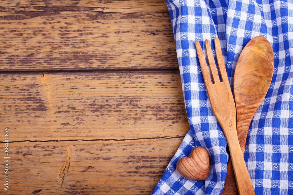 Rustic food background with plaid cloth, wooden spoon, fork and heart on wood Rustic food background with plaid cloth, wooden spoon, fork and heart on wood